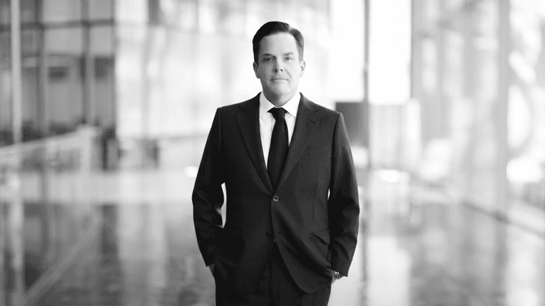 A businessman in a suit stands confidently in a modern, bright interior