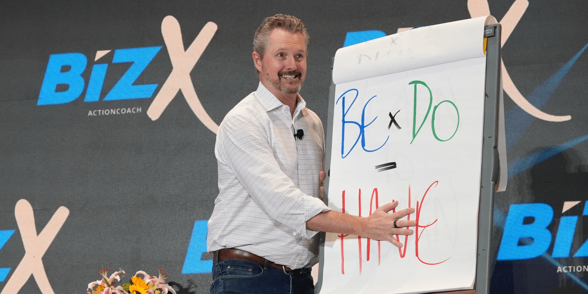 Speaker presenting on stage with a flip chart during a business event