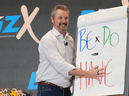 Speaker presenting on stage with a flip chart during a business event