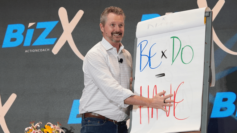 Speaker presenting on stage with a flip chart during a business event
