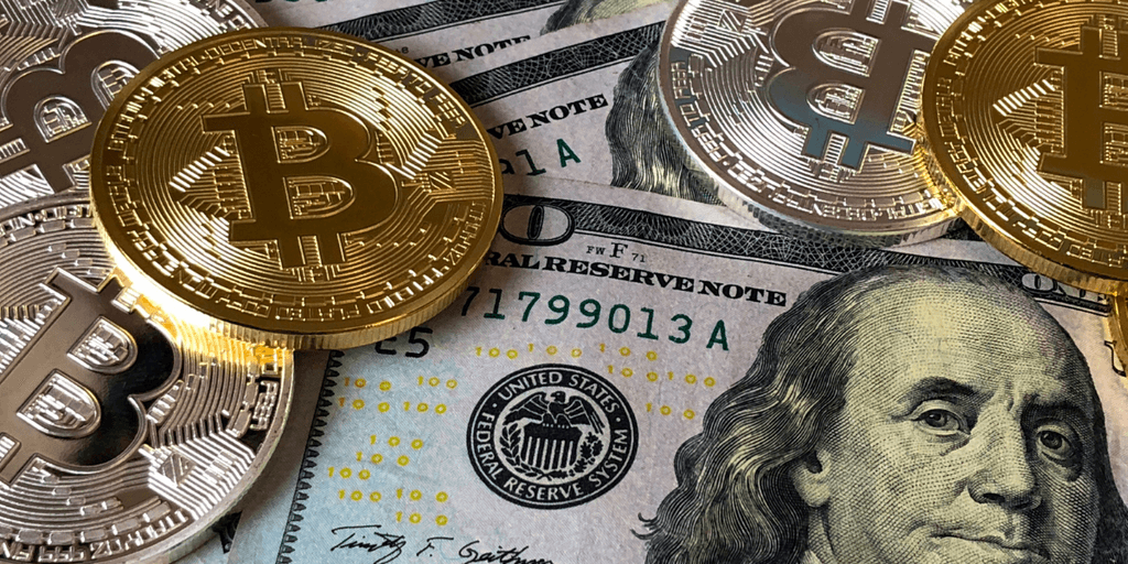 Golden Bitcoin coins on top of U.S. dollar bills with Benjamin Franklin's portrait