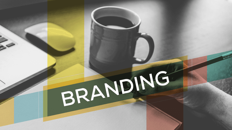 A hand holding a pen beside a coffee cup and laptop, with "BRANDING" overlay