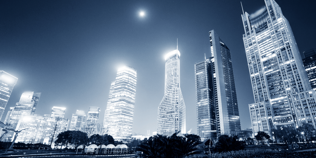 City skyline at night with modern skyscrapers illuminated against a dark sky