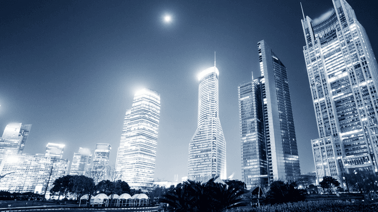 City skyline at night with modern skyscrapers illuminated against a dark sky