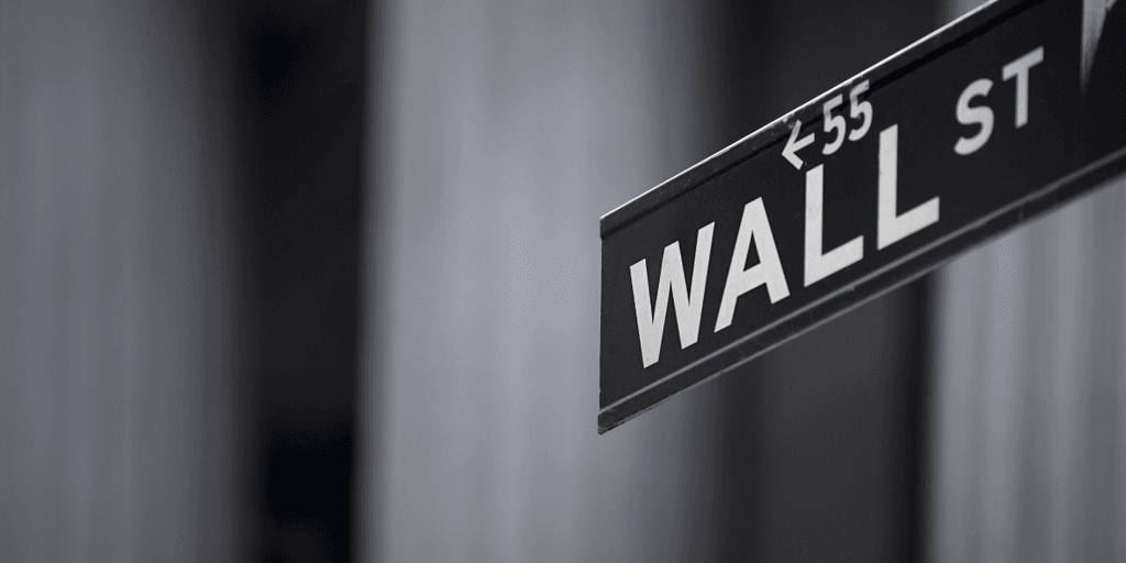 Street sign for Wall Street in a blurred urban backdrop