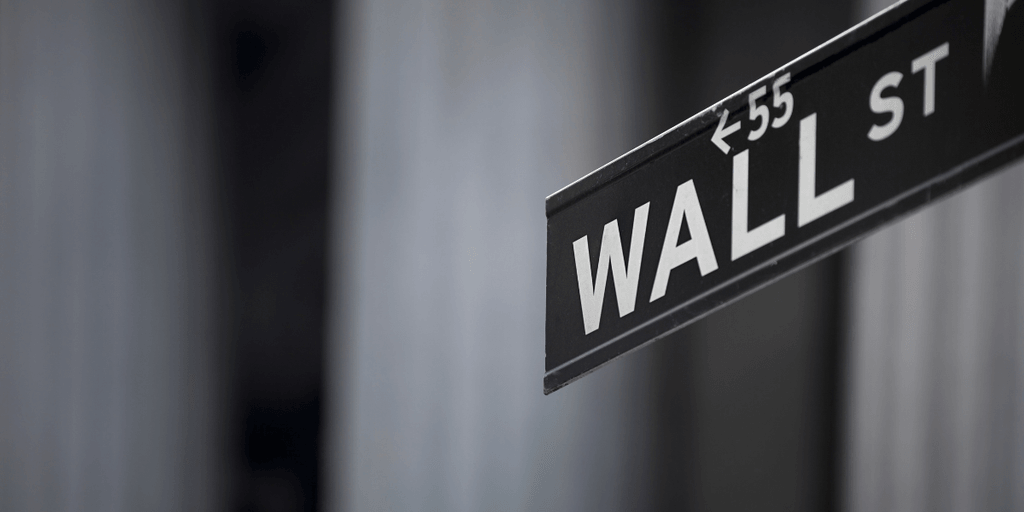 Street sign for Wall Street in a blurred urban backdrop