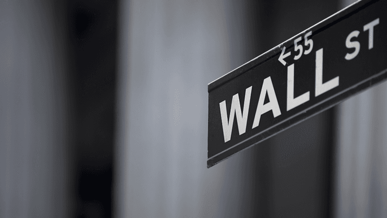 Street sign for Wall Street in a blurred urban backdrop