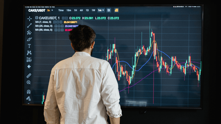 Person analyzing cryptocurrency charts on a digital screen in a modern setting