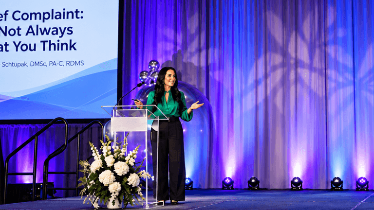 A woman speaking at a podium in front of a presentation screen.