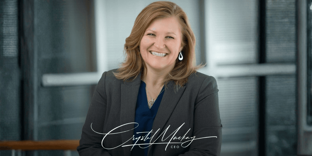 Smiling woman in a blazer poses in an office setting with a professional demeanor