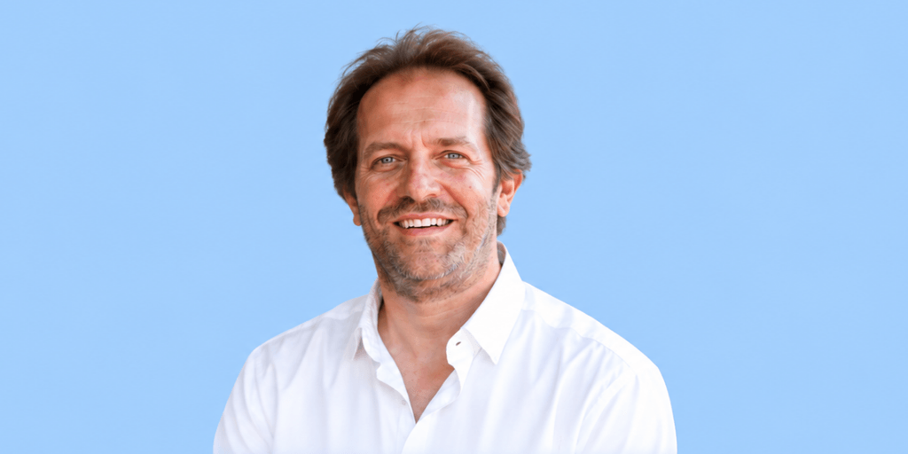 Smiling man in a white shirt against a light blue background