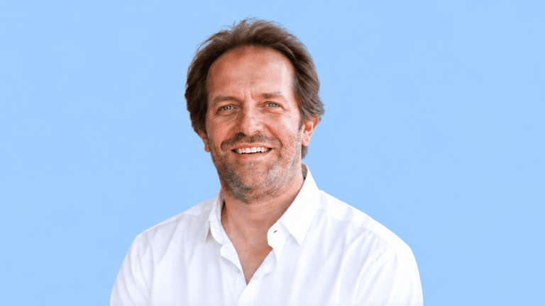Smiling man in a white shirt against a light blue background