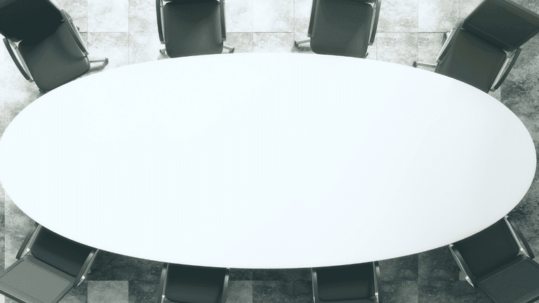 Aerial view of an oval conference table surrounded by black chairs.