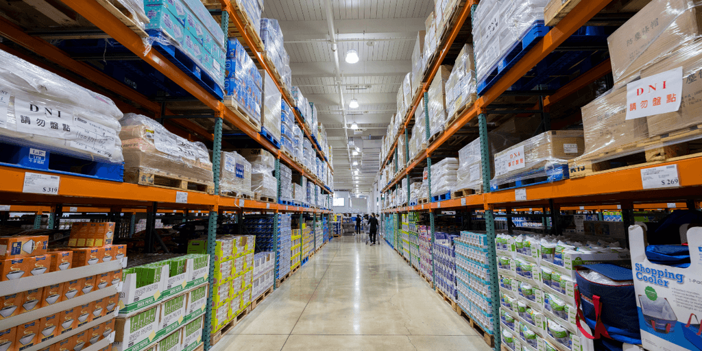 A vast warehouse aisle filled with stacked shelves of various packaged goods