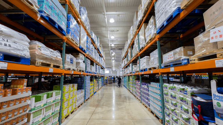 A vast warehouse aisle filled with stacked shelves of various packaged goods