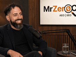 Man with curly hair and beard smiling during a podcast recording in a studio