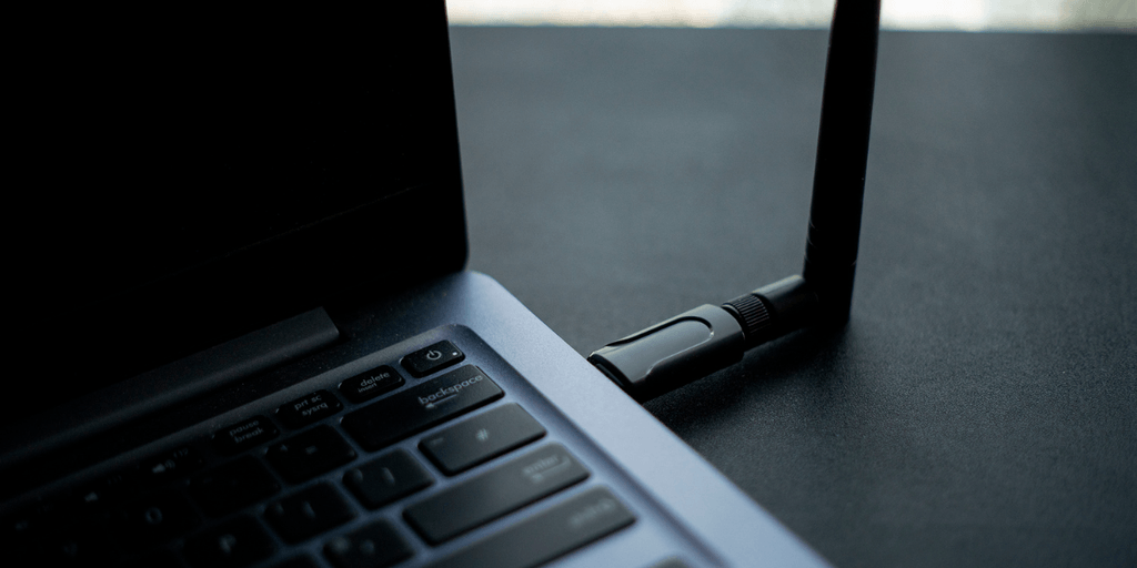 Close-up of a laptop with a USB device plugged in on a dark surface