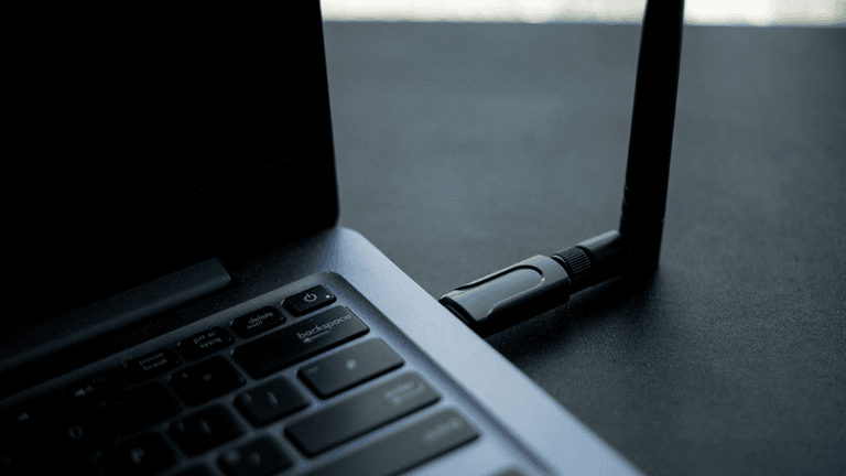 Close-up of a laptop with a USB device plugged in on a dark surface