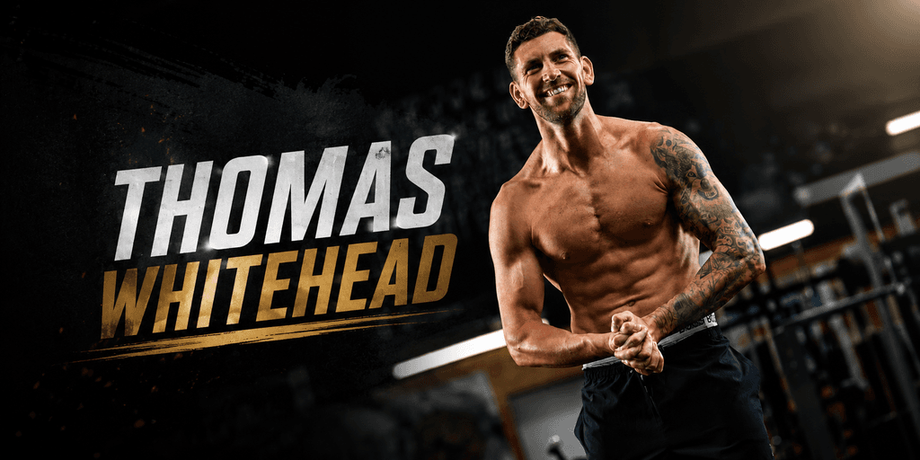 Fit man with tattoos smiling in a gym setting, showcasing strength and positivity