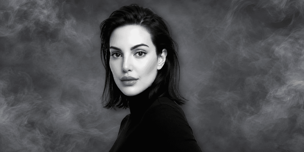 A woman with long dark hair poses against a smoky black background