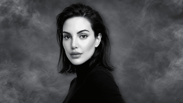 A woman with long dark hair poses against a smoky black background