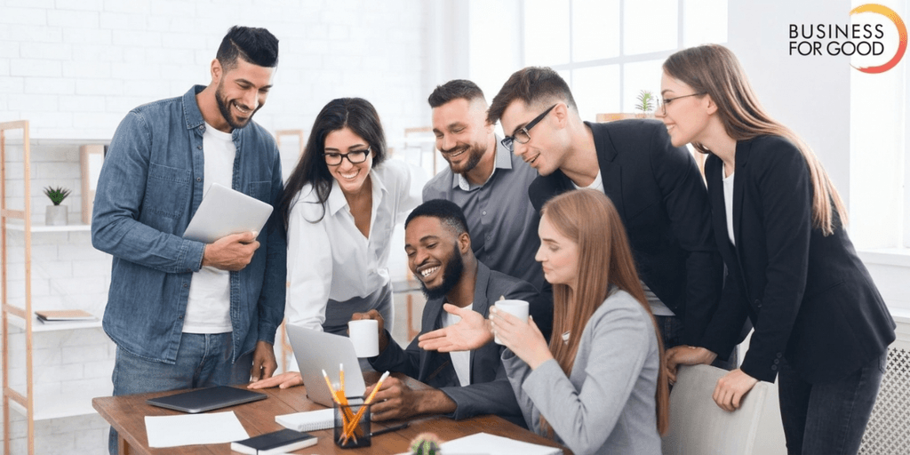 Group of diverse professionals collaborating around a laptop in a modern office setting