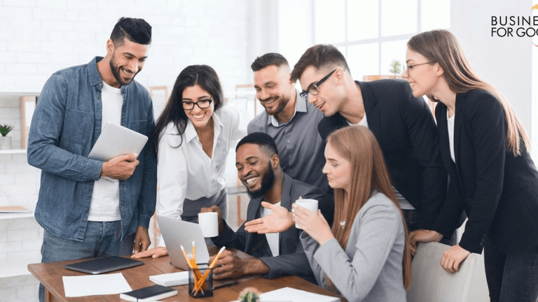 Group of diverse professionals collaborating around a laptop in a modern office setting