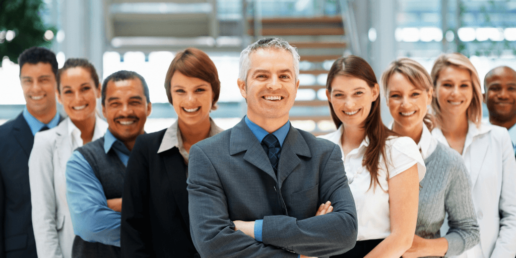 A diverse group of smiling professionals standing together in a modern office setting