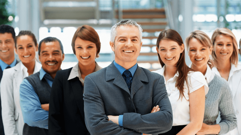 A diverse group of smiling professionals standing together in a modern office setting