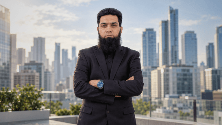 Man in black suit stands confidently on rooftop with city skyline in background