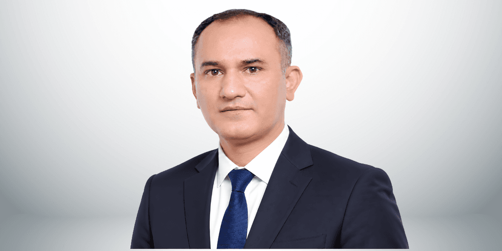 A professional man in a suit with a tie, posing against a neutral background