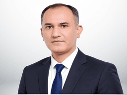 A professional man in a suit with a tie, posing against a neutral background