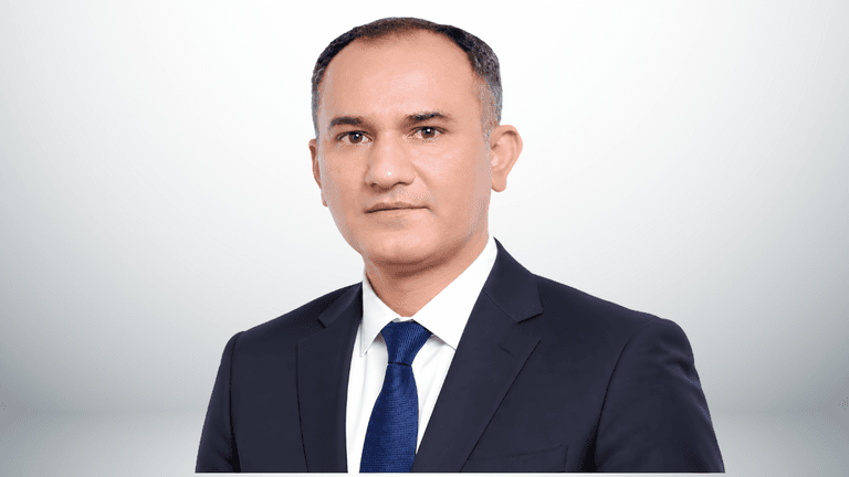 A professional man in a suit with a tie, posing against a neutral background
