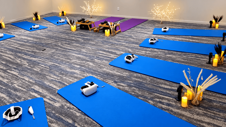 A serene yoga studio with blue mats, VR headsets, candles, and decorative plants