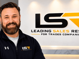 Man smiling in front of a branded wall displaying "LSR Coach" and company slogan