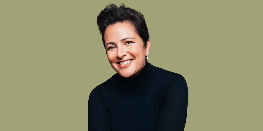 Smiling woman with short dark hair, wearing a black turtleneck against a green background