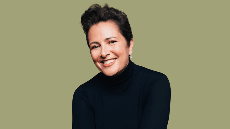 Smiling woman with short dark hair, wearing a black turtleneck against a green background