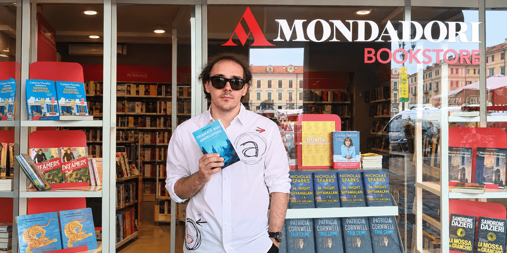 Man holding a book outside a Mondadori bookstore with book displays visible