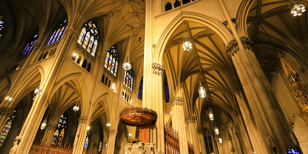 Interior of a grand cathedral featuring tall arches and stained glass windows