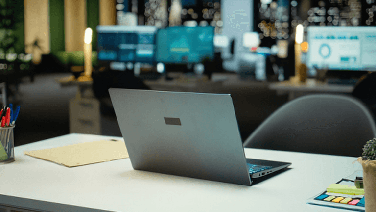 A laptop on a desk in a modern office with city lights in the background