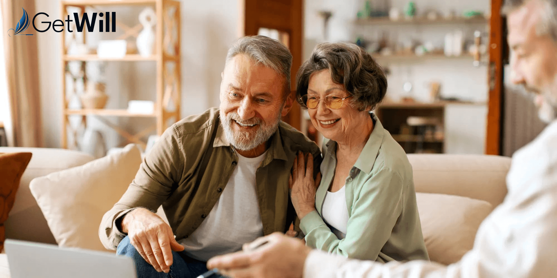 Elderly couple smiling together while using a laptop in a cozy living room