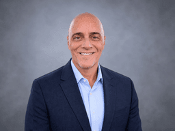 Smiling man in a blazer and shirt against a gray background