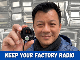 Man holding a device in front of a wall of old radios