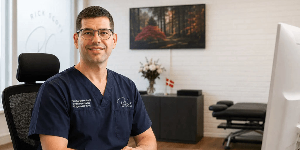Male professional in scrubs smiling in a modern office setting with plants