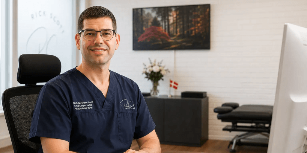 Male professional in scrubs smiling in a modern office setting with plants