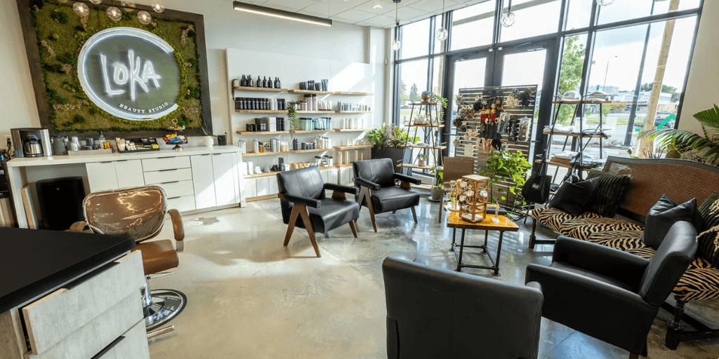Modern beauty salon interior with sleek furniture, greenery, and a moss wall displaying 'LOKA Beauty Studio' logo.