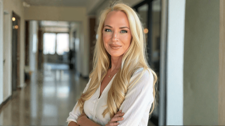 Professional portrait of Donnalynn Patakos, founder of Portray Art Advisory, standing confidently in a modern office hallway, symbolizing art investment leadership.