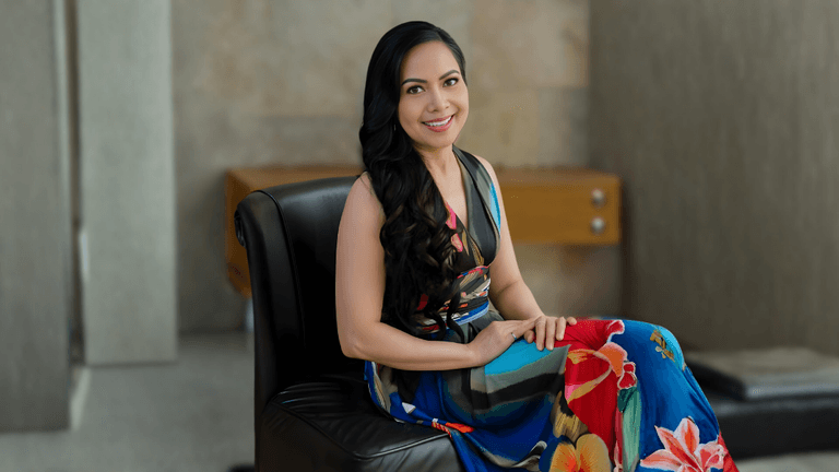 Liza Baliad, founder of Renew by Liz, seated in a vibrant dress, embodying beauty, purpose, and sustainable skincare