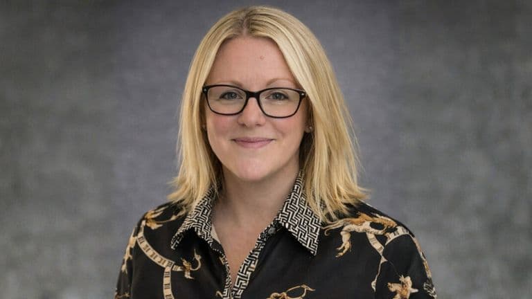 Hannah Hally, founder of The Business Book Club, wearing a patterned blouse, smiling confidently with a professional backdrop.