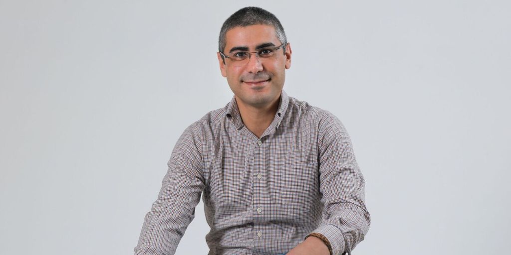 Portrait of entrepreneur and business coach Jad Atwe smiling against a plain gray background.